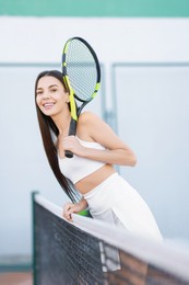 Beautiful woman with tennis racket on court