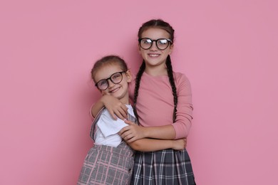 Portrait of cute little sisters on pink background