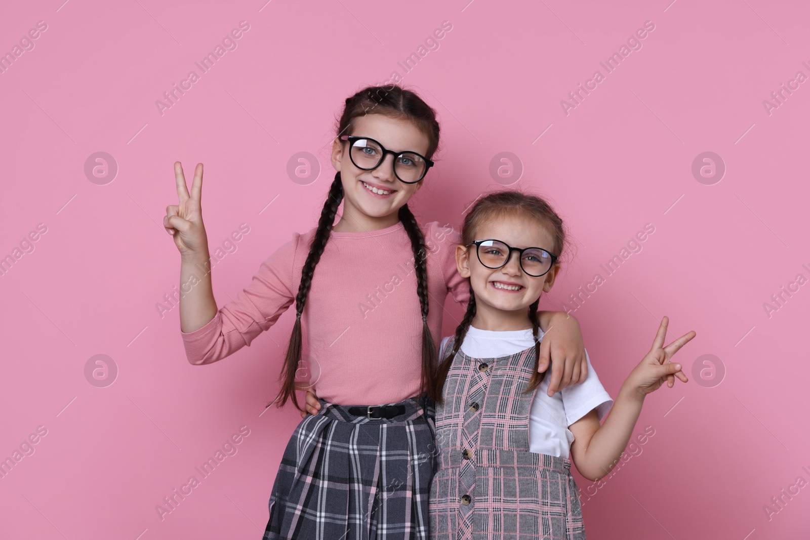 Photo of Portrait of cute little sisters on pink background