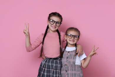 Portrait of cute little sisters on pink background