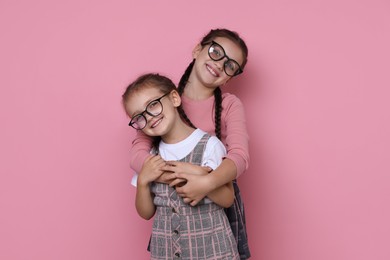 Portrait of cute little sisters on pink background