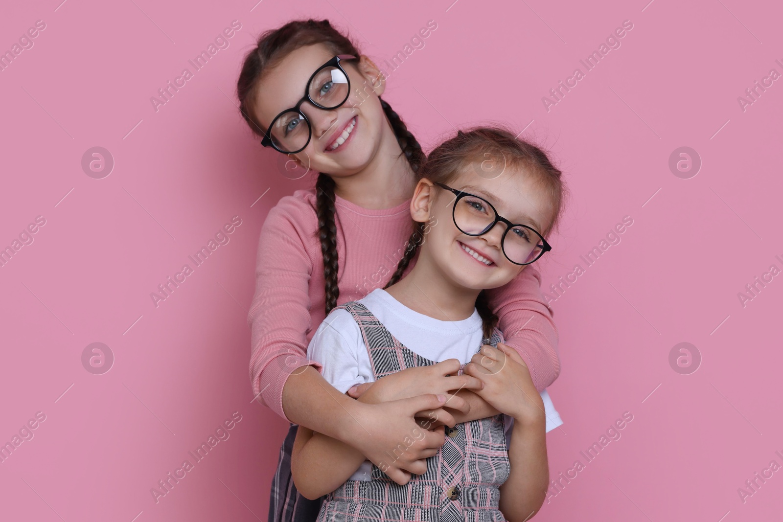 Photo of Portrait of cute little sisters on pink background