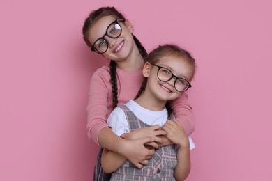 Portrait of cute little sisters on pink background