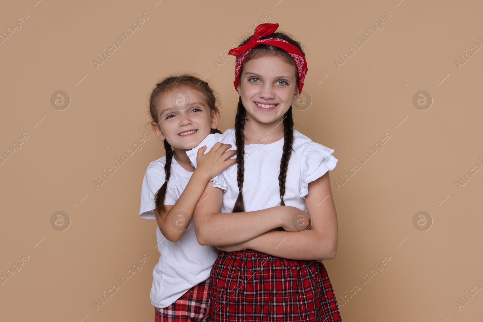 Photo of Portrait of cute little sisters on beige background