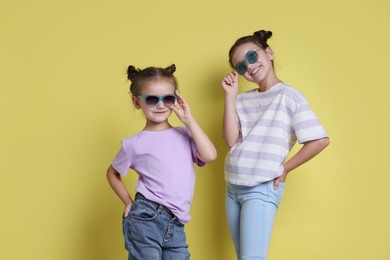 Photo of Portrait of cute little sisters on yellow background