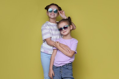 Portrait of cute little sisters on yellow background