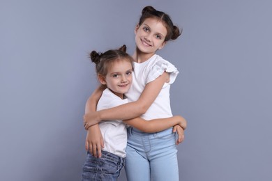 Photo of Portrait of cute little sisters on grey background