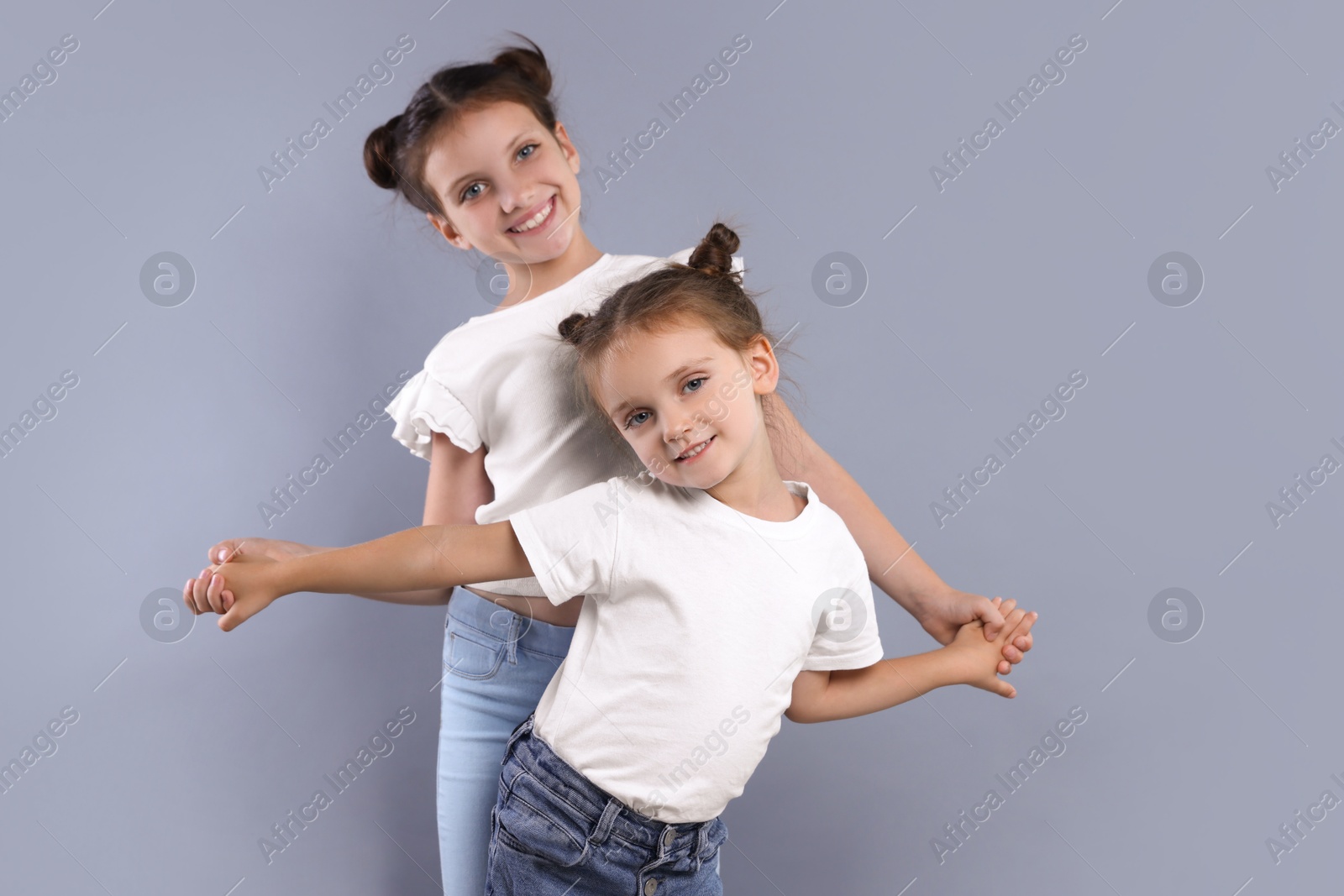 Photo of Portrait of cute little sisters on grey background