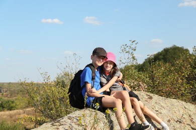 Little brother and sister hugging on stone