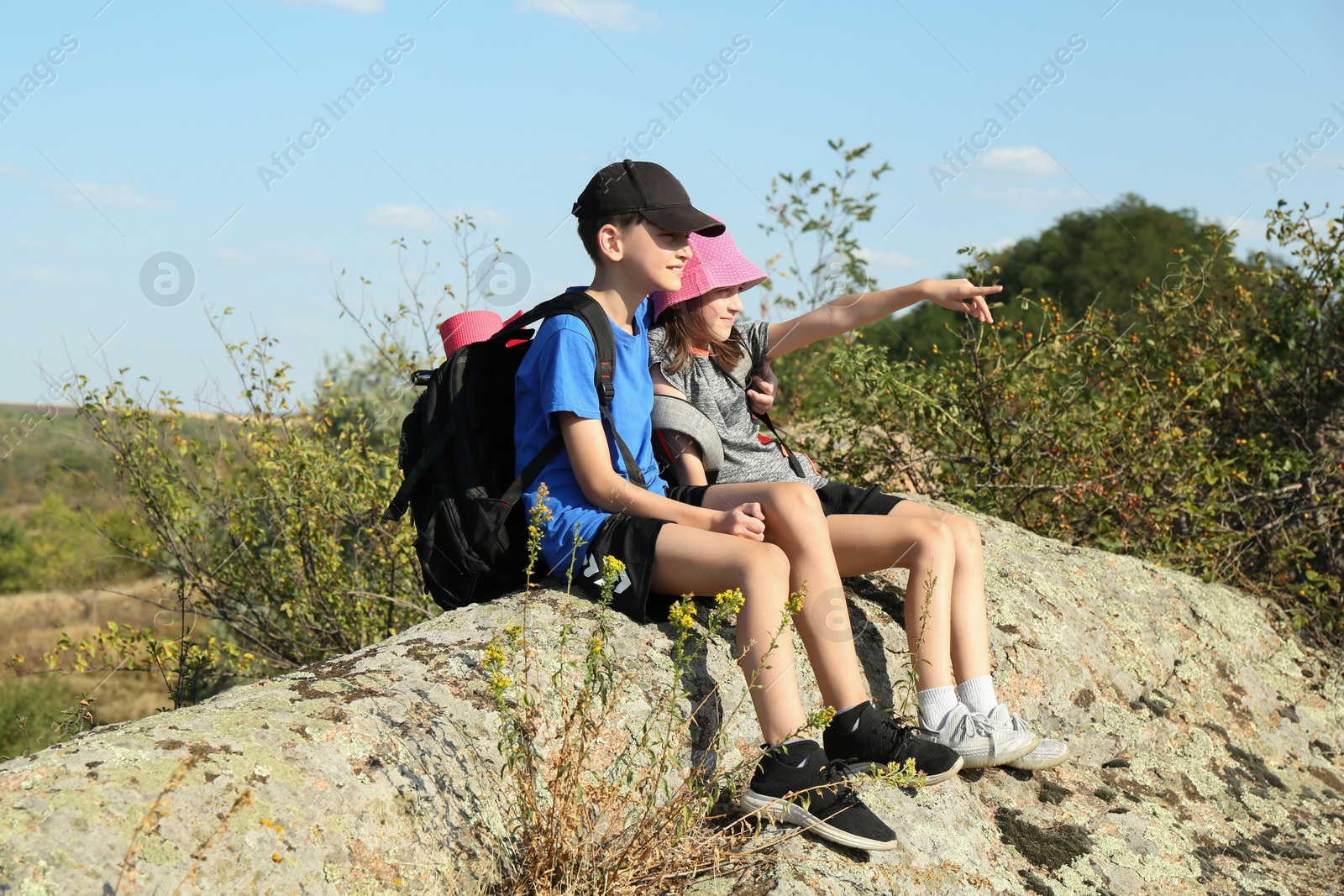 Photo of Happy brother and sister enjoying picturesque landscape on stone