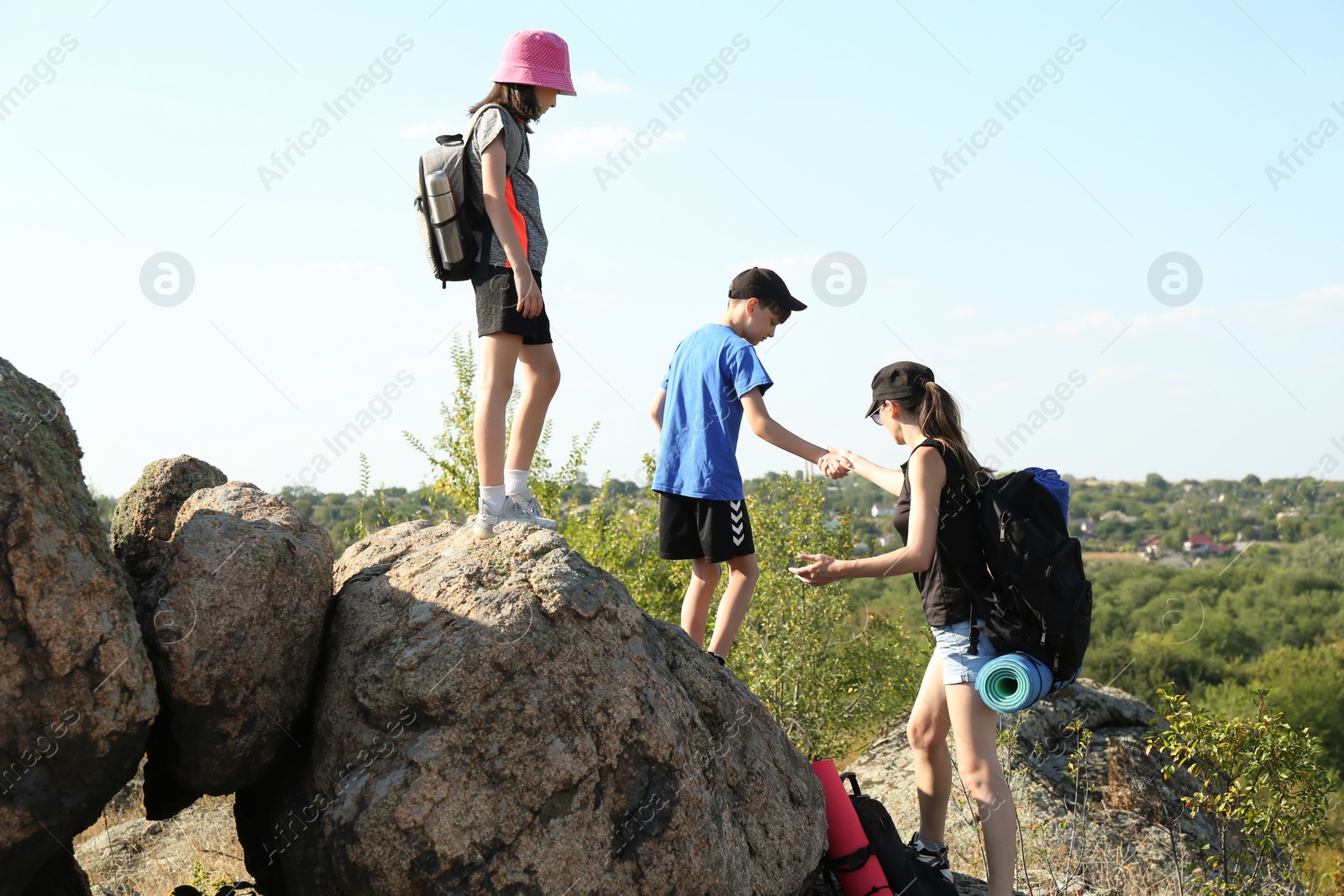 Photo of Family with backpacks climbing on stones outdoors