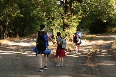 Family with backpacks travelling in beautiful forest, back view