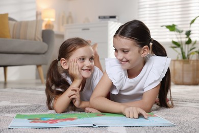 Cute little sisters reading book at home