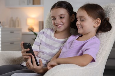 Cute little sisters using smartphone at home