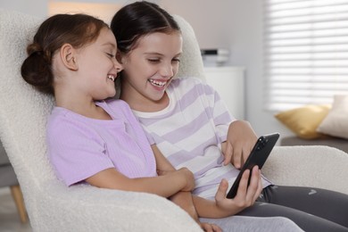 Cute little sisters using smartphone at home