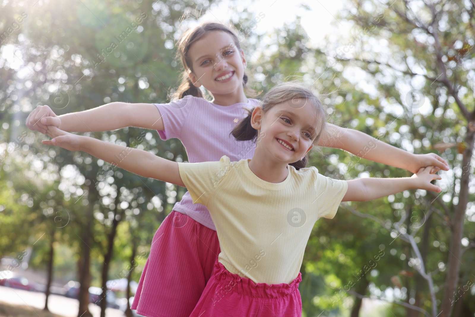 Photo of Cute little sisters spending time together in park, low angle view