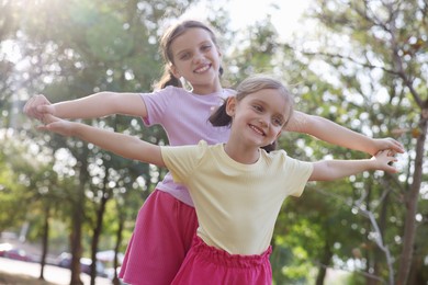 Cute little sisters spending time together in park, low angle view