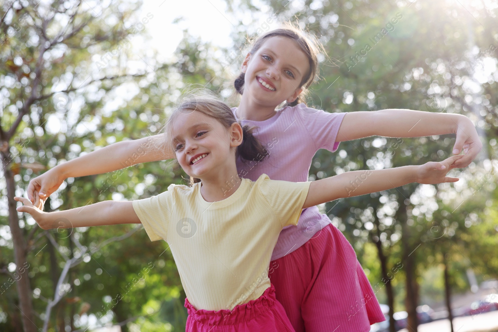 Photo of Cute little sisters spending time together in park, low angle view