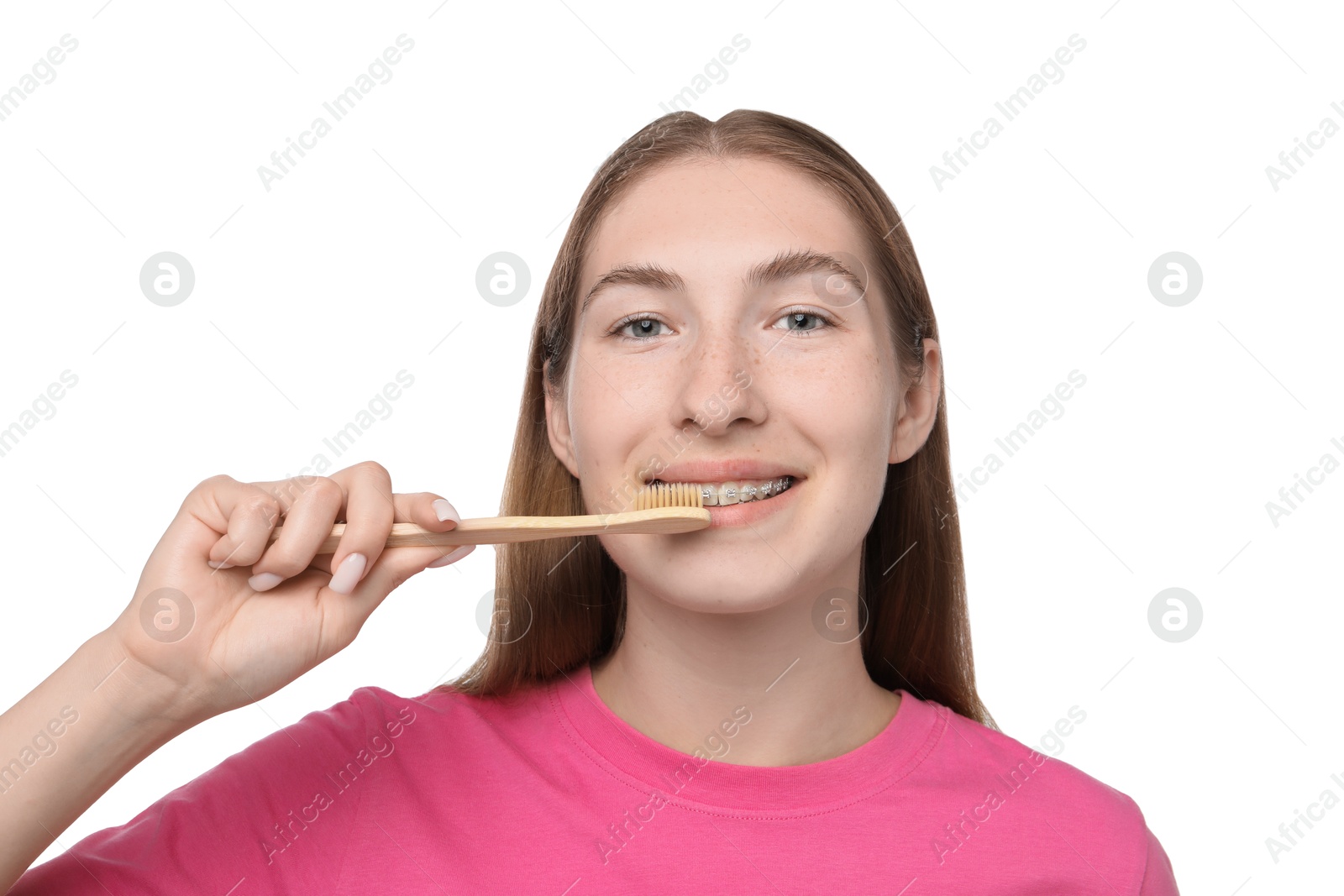 Photo of Smiling girl with braces cleaning teeth on white background