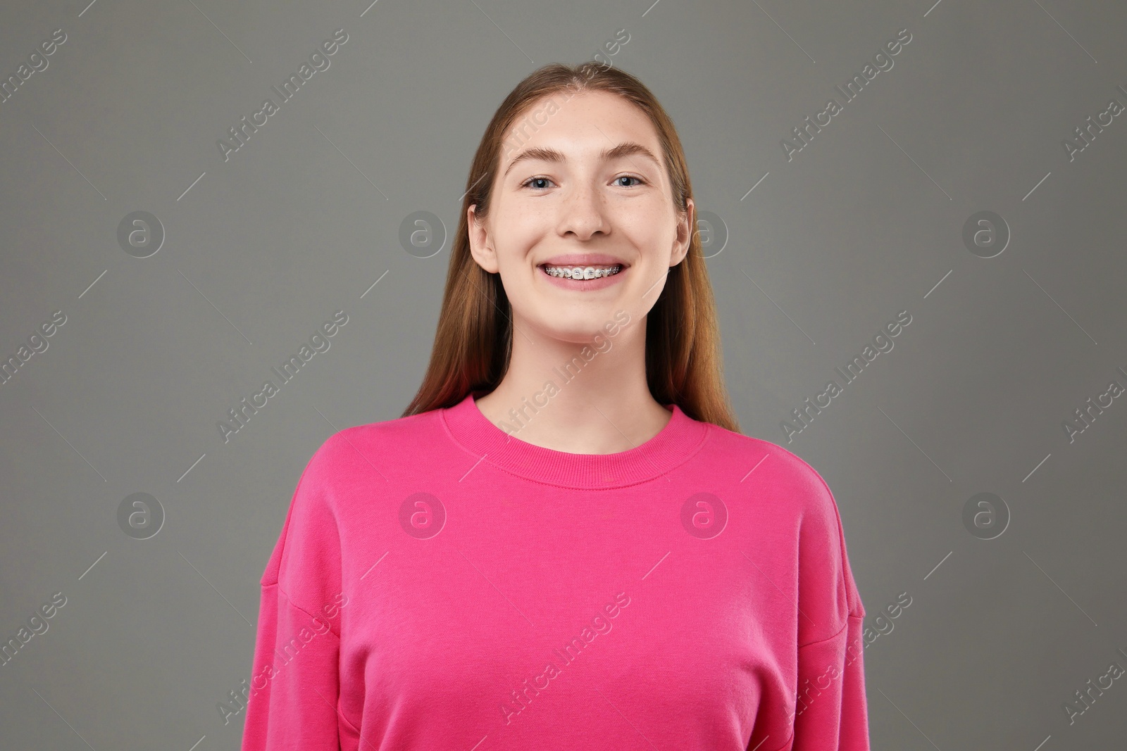 Photo of Smiling girl with braces on grey background