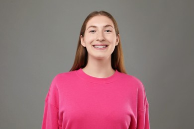 Photo of Smiling girl with braces on grey background