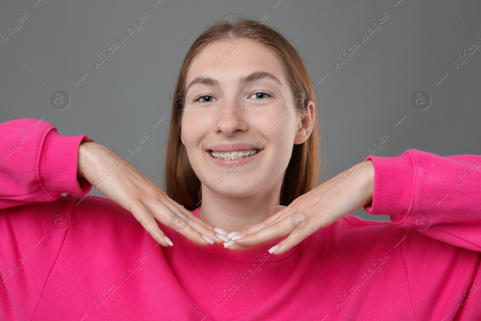 Photo of Smiling girl with braces on grey background