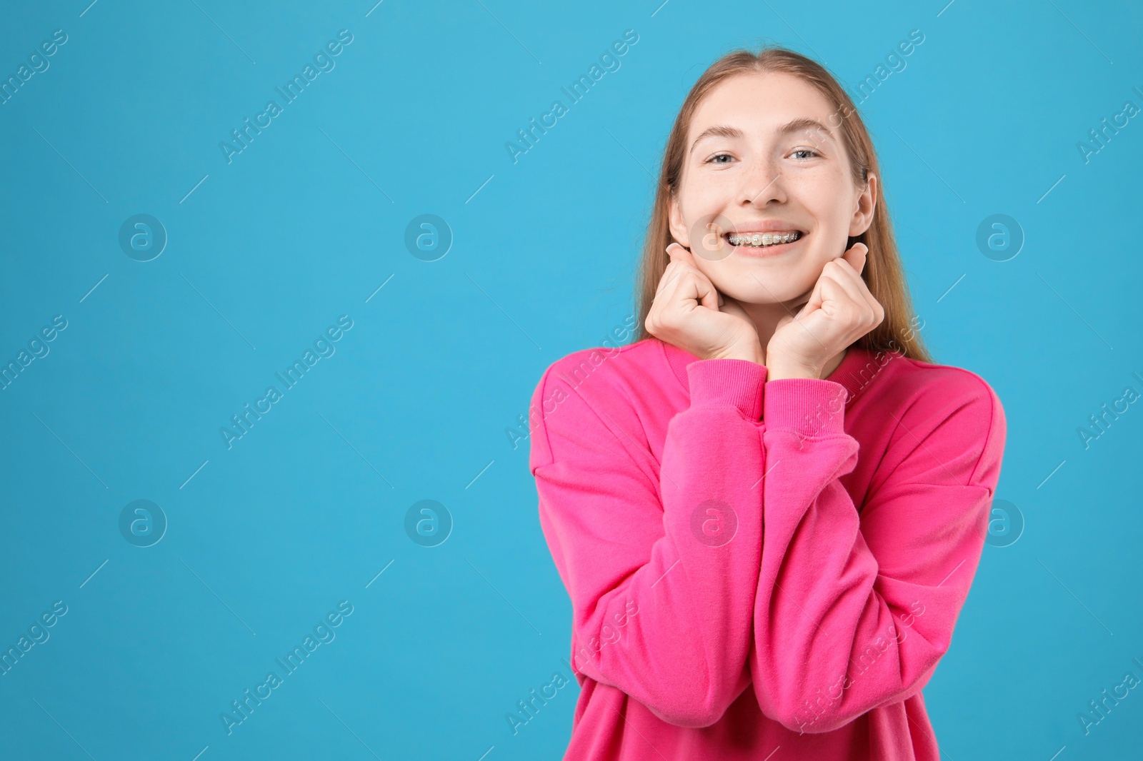 Photo of Smiling girl with braces on light blue background, space for text