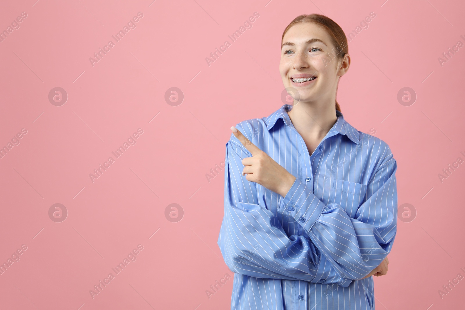 Photo of Smiling girl with braces on pink background, space for text