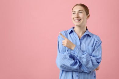 Photo of Smiling girl with braces on pink background, space for text