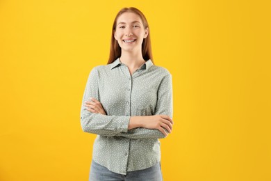 Photo of Smiling girl with braces on orange background