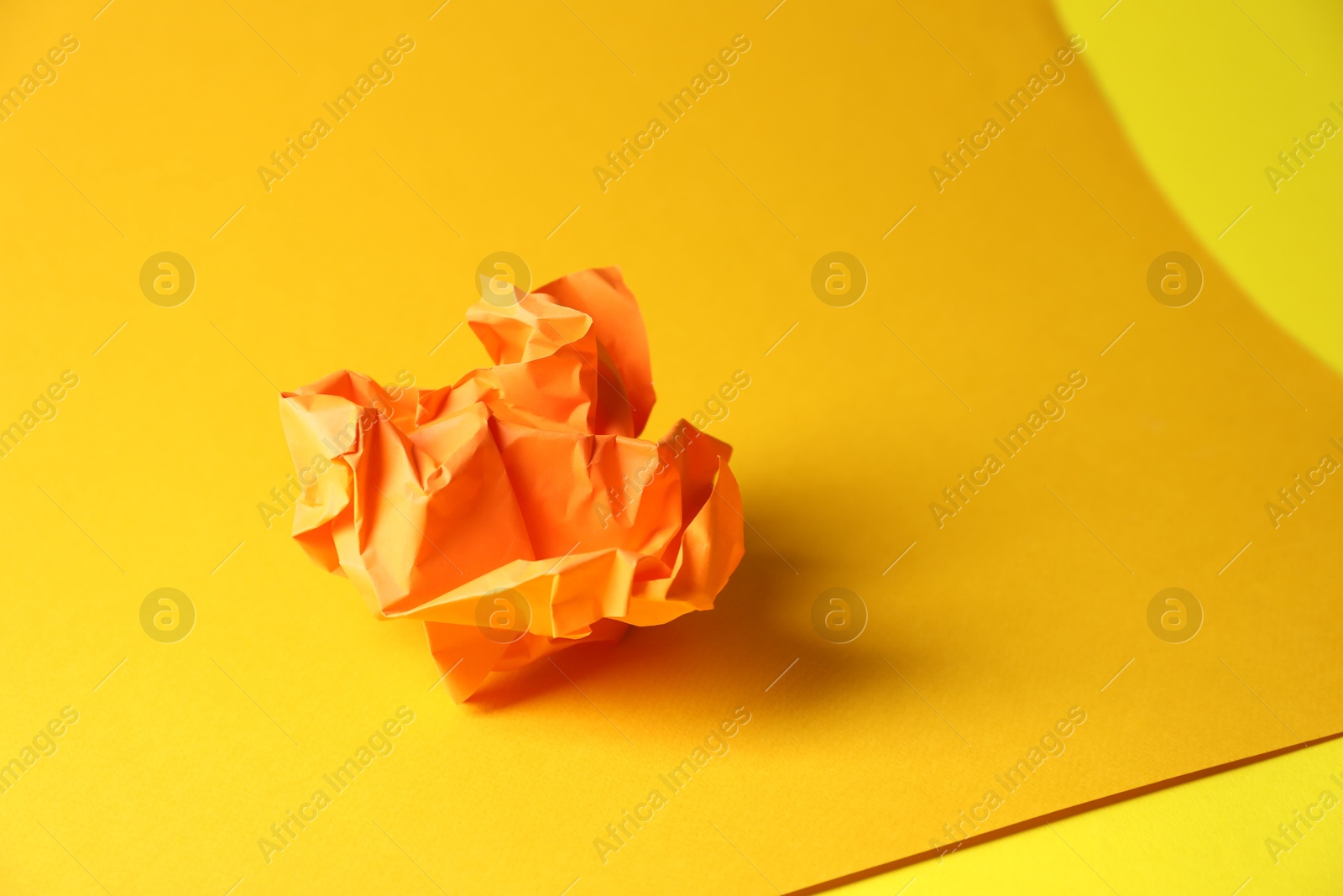 Photo of Orange crumpled paper on yellow background, space for text