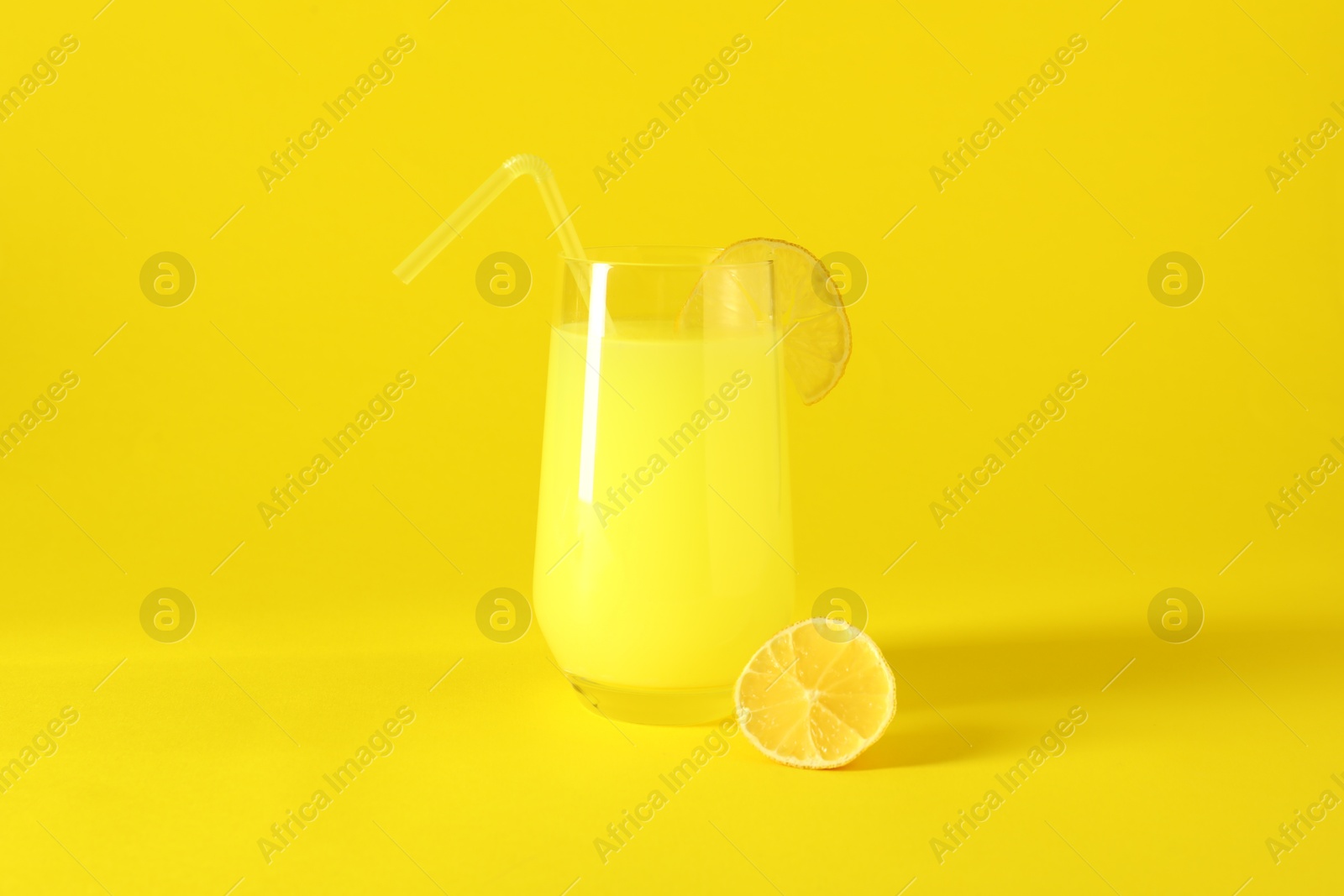 Photo of Fresh juice in glass and lemon on yellow background