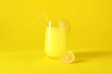 Fresh juice in glass and lemon on yellow background