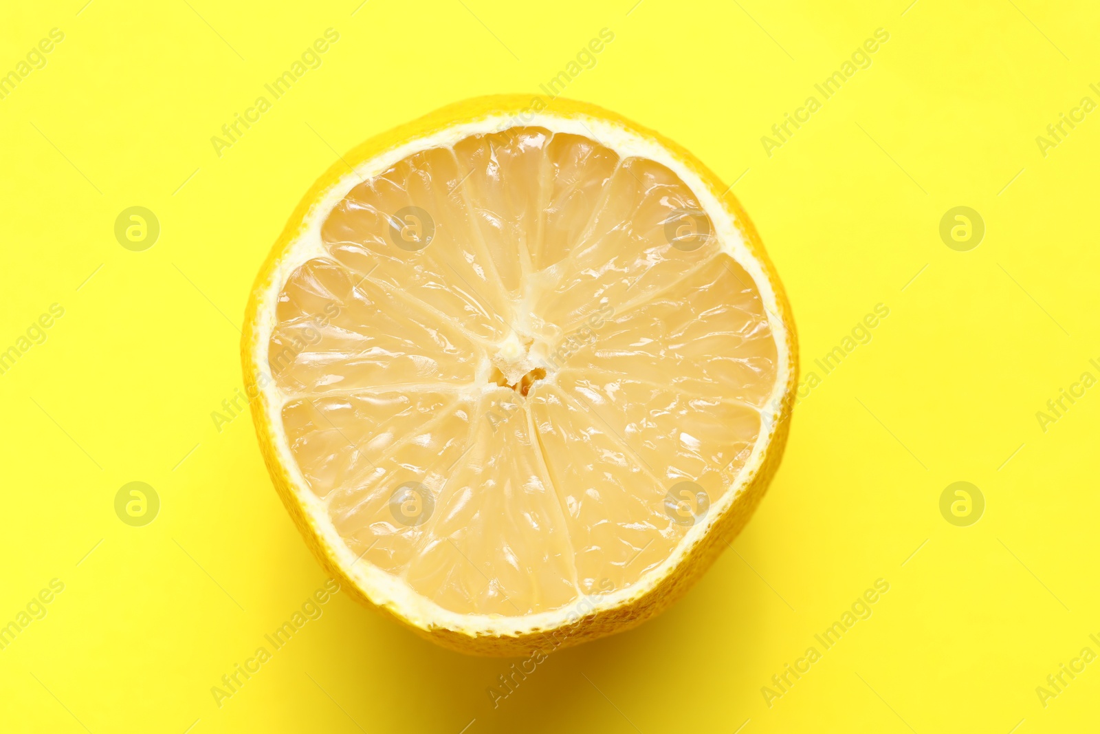 Photo of Fresh lemon half on yellow background, top view