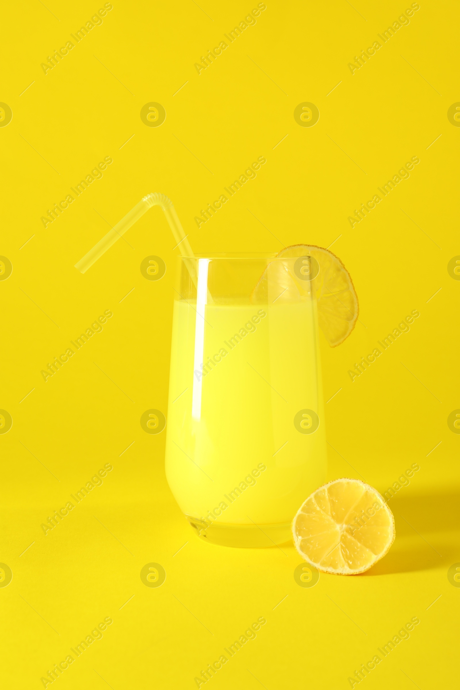 Photo of Fresh juice in glass and lemon on yellow background