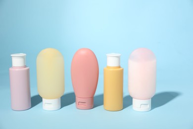 Photo of Bottles of different skin care products on light blue background