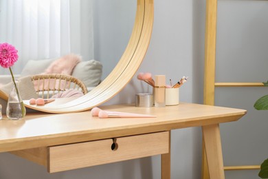 Photo of Dressing table with mirror, cosmetic products and flower indoors. Interior design