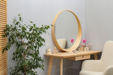 Mirror, dressing table, houseplant and armchair indoors. Interior design