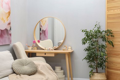 Mirror, dressing table, houseplant, sofa and armchair indoors. Interior design