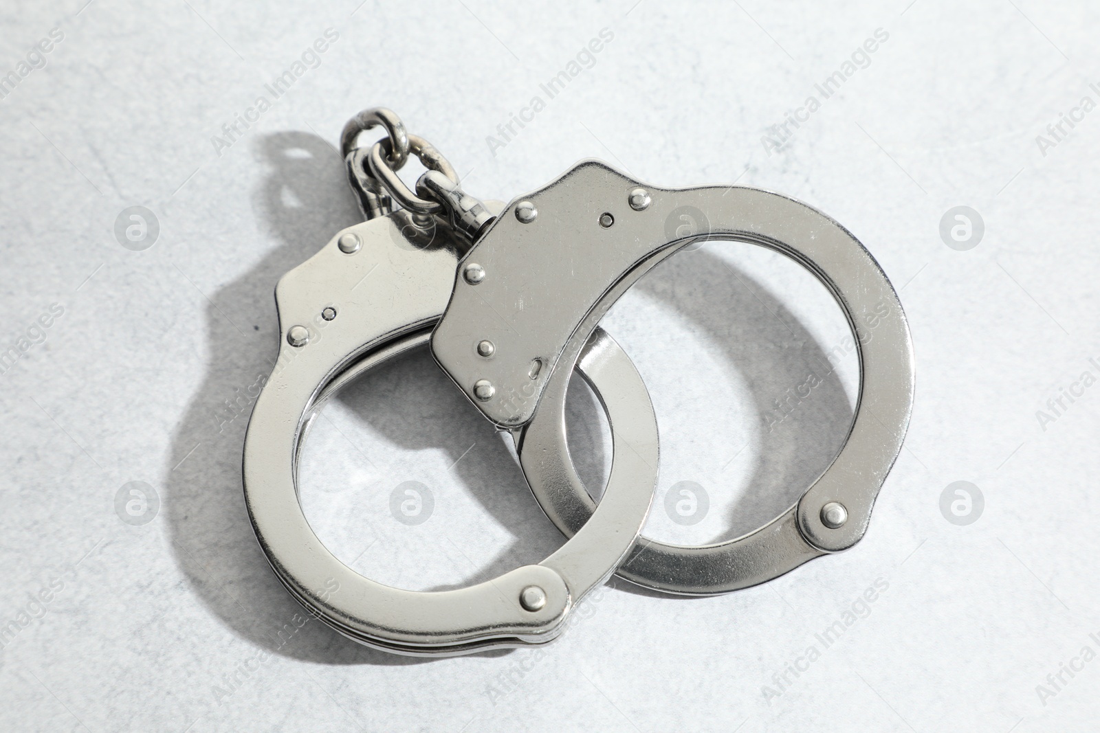 Photo of Metal chain handcuffs on light grey table, above view