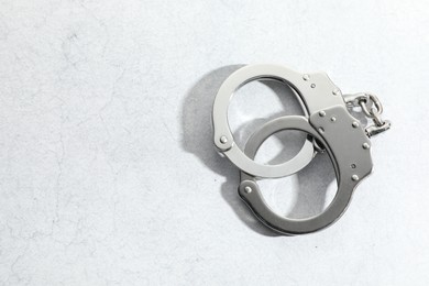 Photo of Metal chain handcuffs on light grey table, top view. Space for text