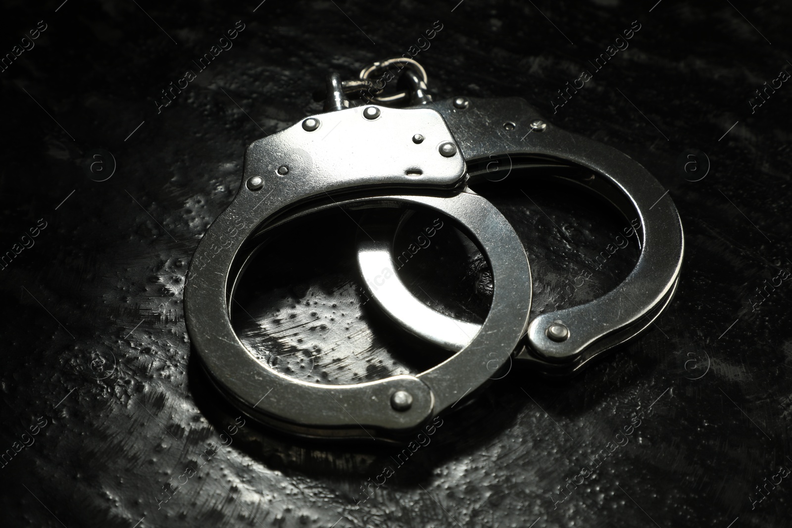 Photo of Metal chain handcuffs on black table, closeup