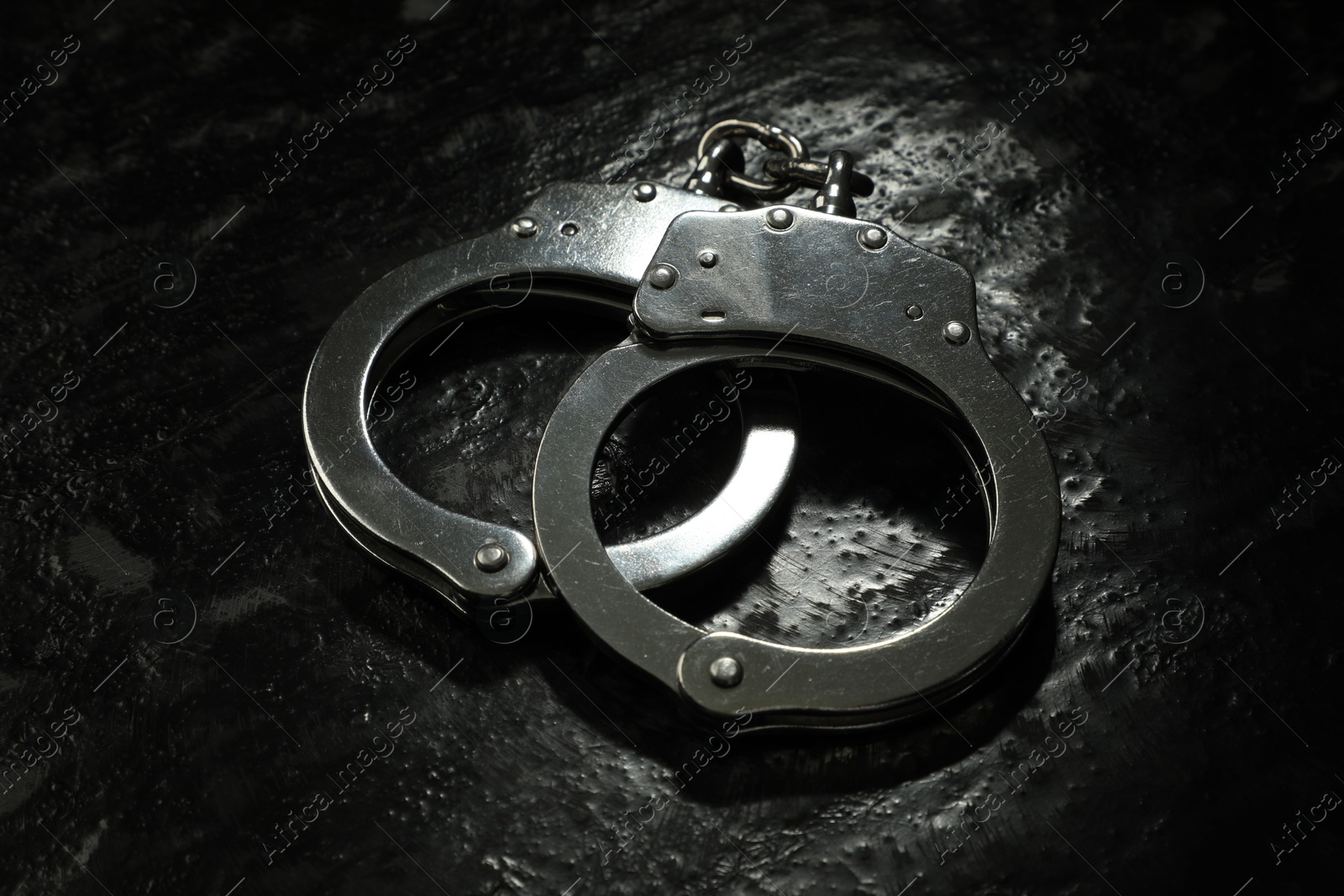 Photo of Metal chain handcuffs on black table, closeup