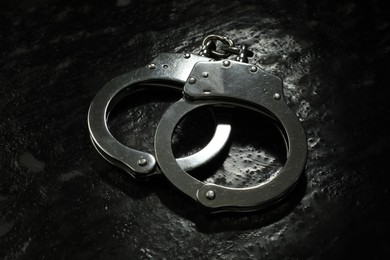 Photo of Metal chain handcuffs on black table, closeup