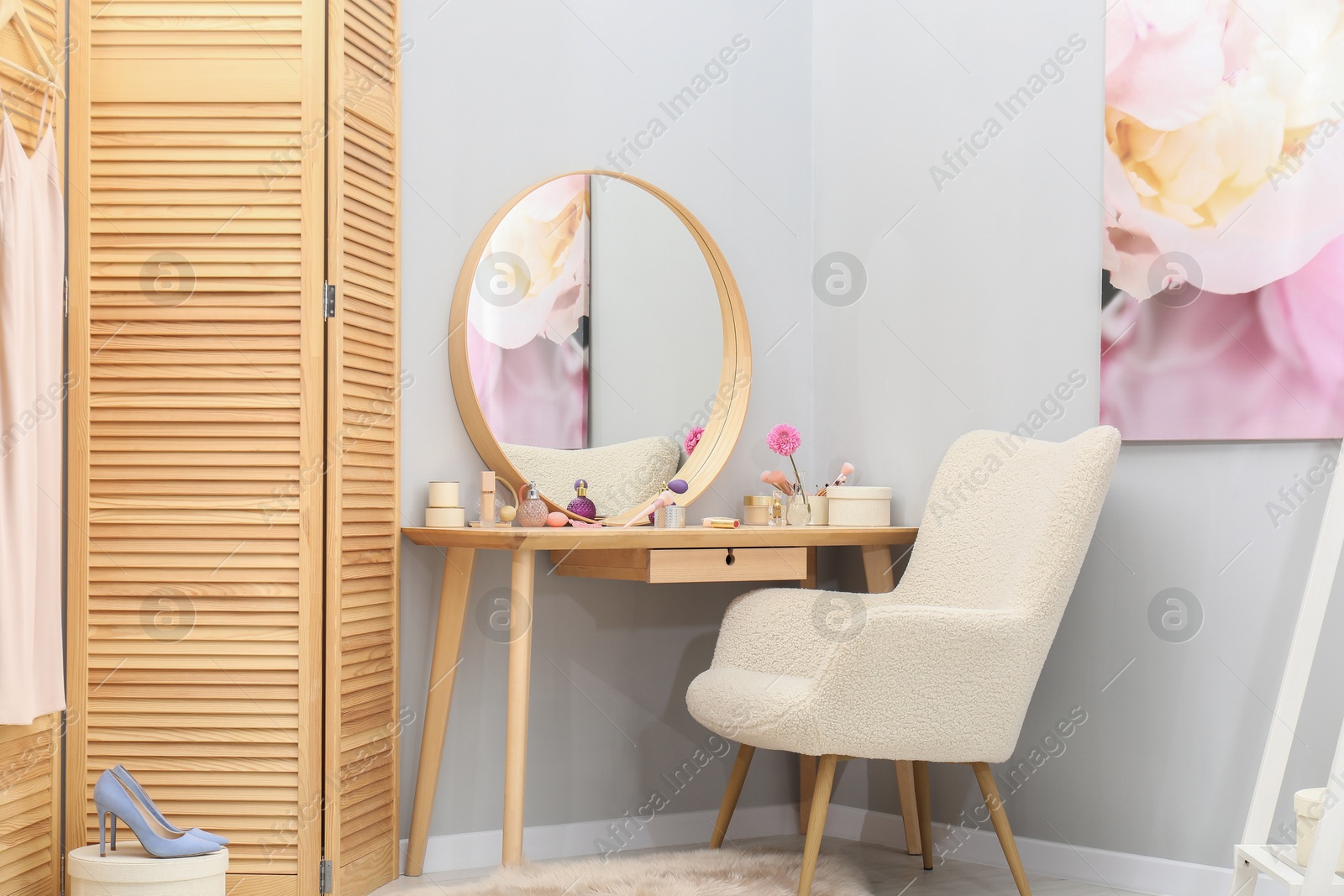 Photo of Mirror, dressing table with cosmetic products, armchair and folding screen indoors. Interior design