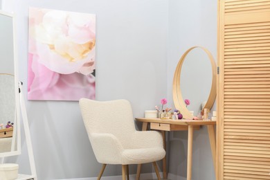 Photo of Mirrors, dressing table with cosmetic products, armchair and folding screen indoors. Interior design