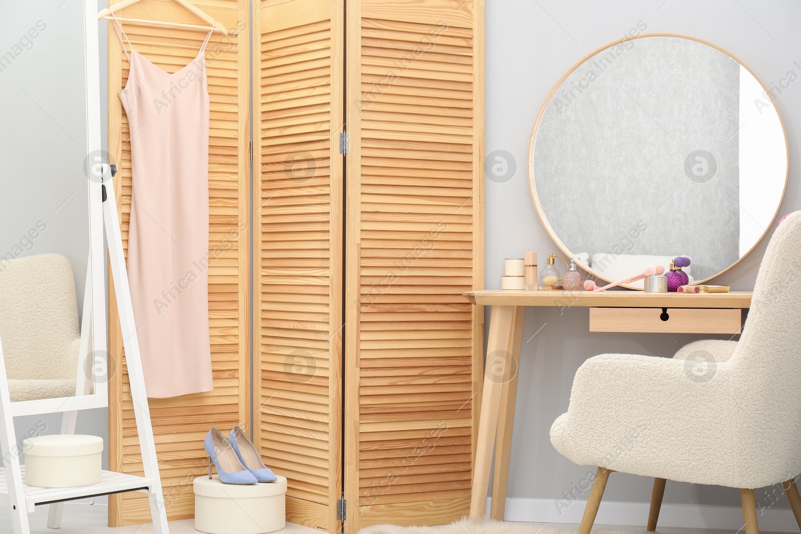 Photo of Mirrors, dressing table with cosmetic products, armchair and folding screen indoors. Interior design