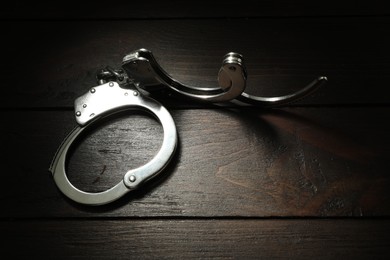 Photo of Metal chain handcuffs on wooden table, top view