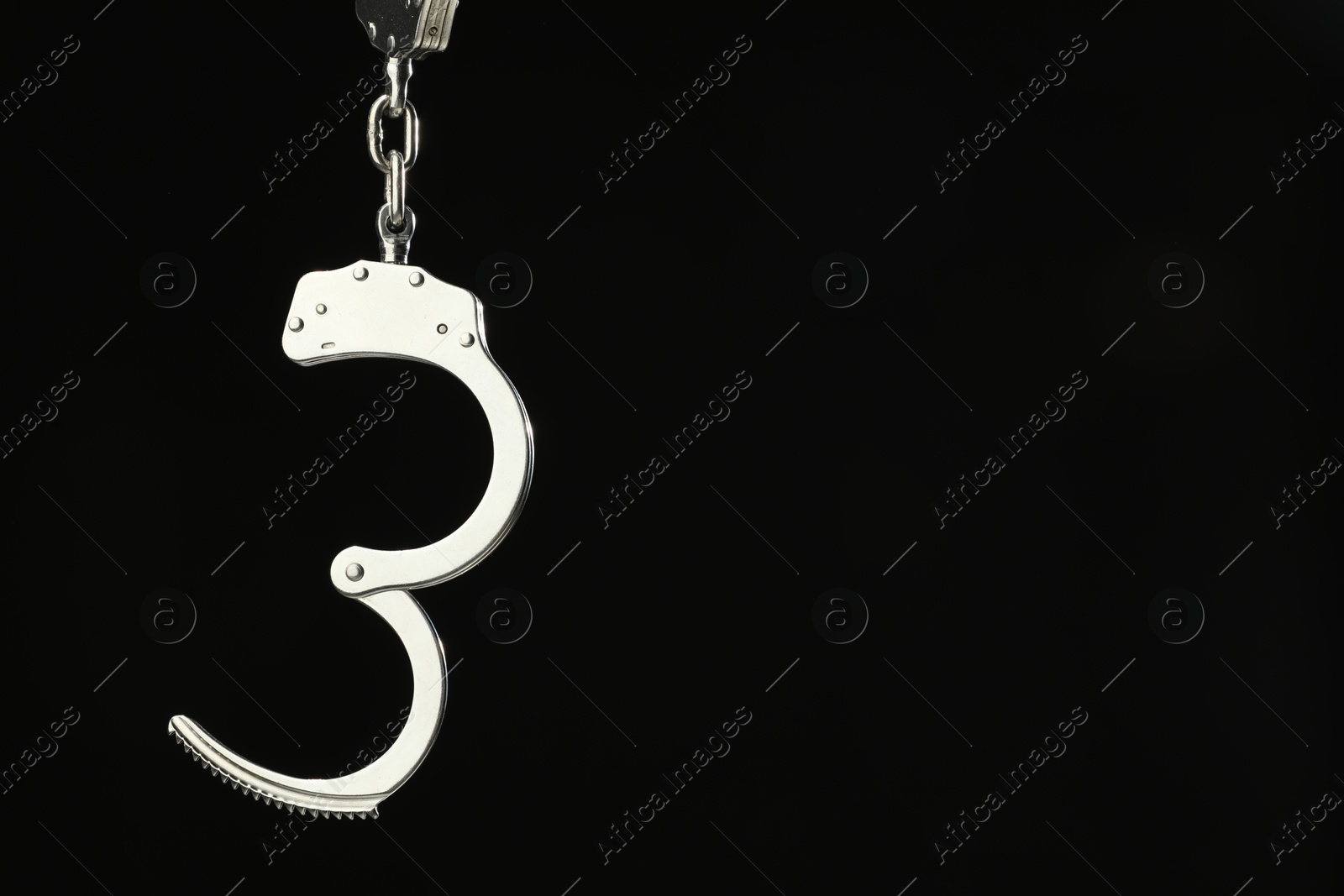 Photo of Metal chain handcuffs on black background, closeup. Space for text