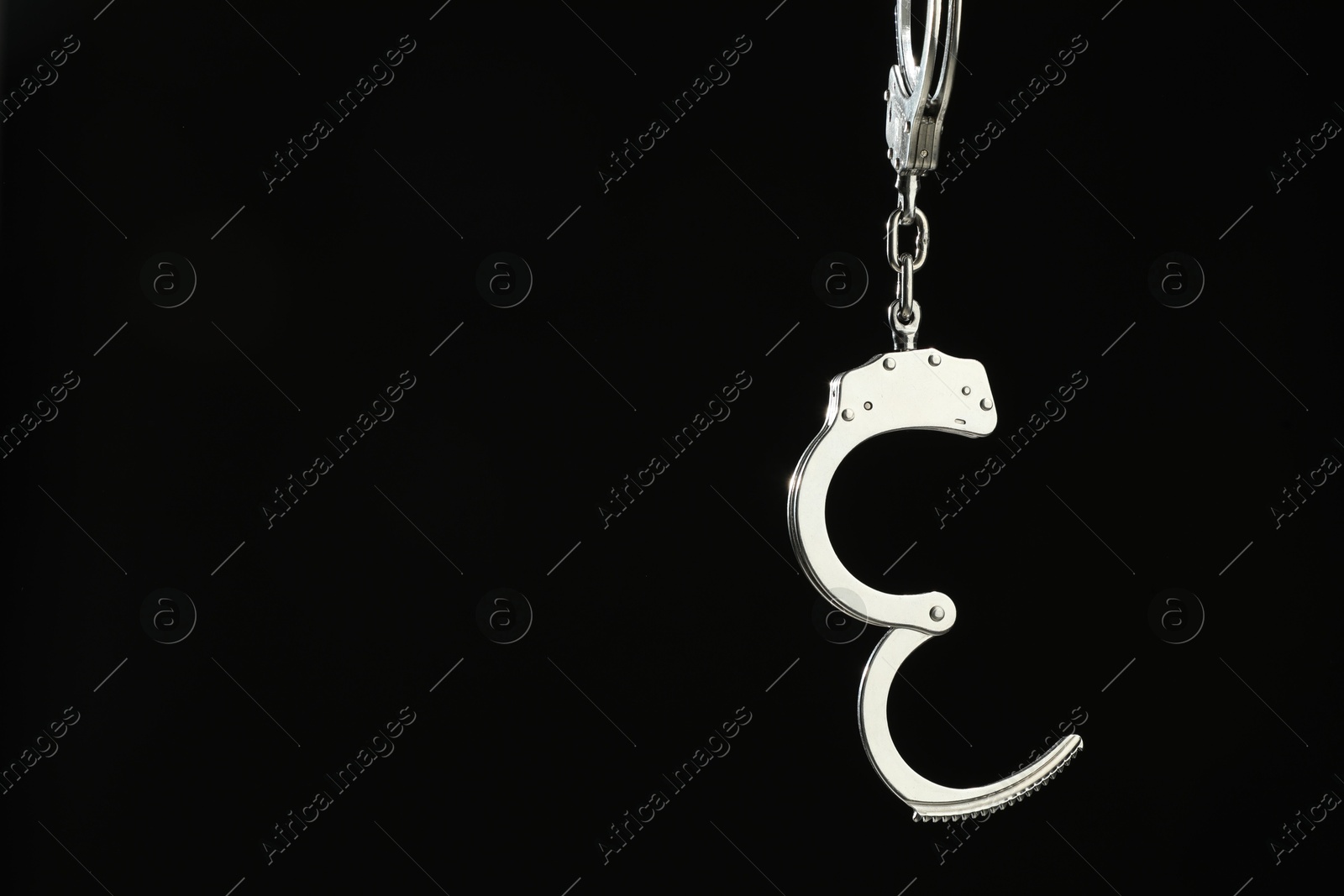 Photo of Metal chain handcuffs on black background, closeup. Space for text